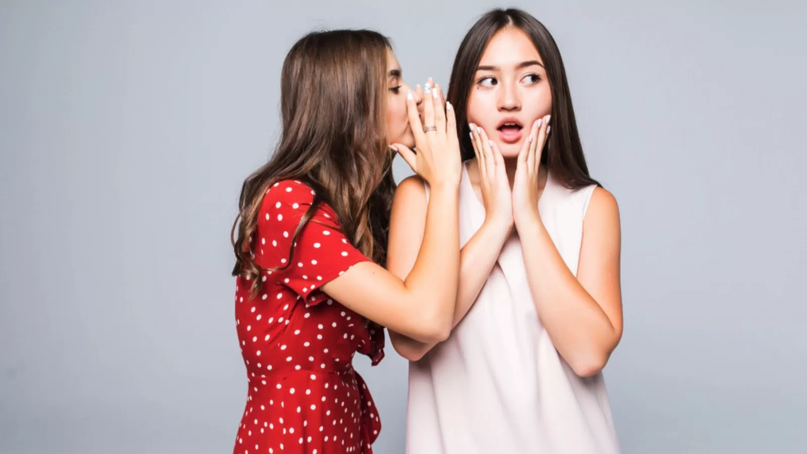 Woman telling secret to another woman